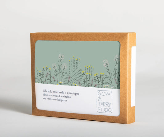 A boxed set of blank notecards, printed with a hand-drawn illustration of a tall-grass prairie on uncoated, recyclable paper. Packaged in a compostable box.
