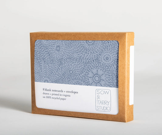 A boxed set of blank notecards, printed with a hand-drawn illustration of a blue starry night on uncoated, recyclable paper. Packaged in a compostable box.